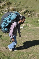 Selective focus of Full length side view of a young man walking in the mountain with carrying parachute backpack
