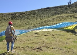 A unidentified male paraglider preparing parachute for flight in the sky