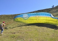 Selective focus of a unidentified male paraglider preparing parachute for flight in the sky