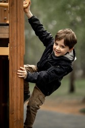 boy playing on the children's playground, a boy on a playground in the park climbs up a climbing wall