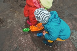 Children in bright rubber boots jump in the puddle closeup no face