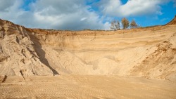 sand quarry, in the photo sand mountain in the quarry in the background blue sky and clouds bottom view.
