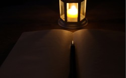 Candle Lantern, Blank Notebook And Pen Concept In Dark Atmosphere