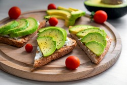 Healthy avocado toast with soft cheese, sliced avocado, cherry tomatoes and pepper on whole grain bread. Healthy nutrition, keto diet or easy recipe of vegaterian sandwich for vegan menu.