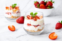 Berry dessert in glass with fresh strawberry, biscuit and whipped cream. Vegan lactose free dessert with alternative milk of coconut. Recipe of healthy organic dessert, cheesecake or berry trifle cake