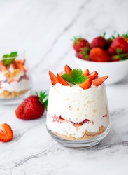 Traditional English strawberry trifle. Individual glass with healthy dessert of yogurt, granola and fresh strawberry. Recipe of simple homemade dessert, cheesecake, mousse on low calorie diet.