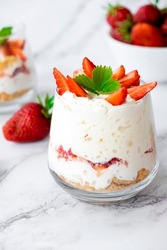 Strawberry trifle dessert with custard, cake crumb and fresh strawberry in glass on marble. Recipe of simple layered dessert with fresh berry and jam. Lactose free cheesecake, vegan dessert tiramisu.