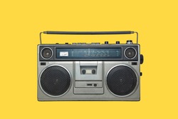 RADIO CASSETTE PLAYER ISOLATED ON YELLOW BACKGROUND. URBAN MUSIC FASHION FROM THE EIGHTIES.