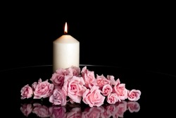 LIGHTED CANDLE AND ELEGANT PINK ROSES ARRANGEMENT ON DARK BACKGROUND. CONDOLENCE CARD, ALL SOULS DAY, DEATH, DECEASE, PRAYER, MEMORIAL DAY, DUEL, MOURNING, GRAVE, CEMETERY, BURIAL AND FUNERAL CONCEPT.