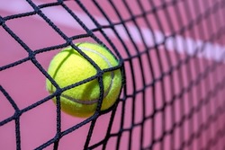 CLOSEUP OF A TENNIS OR PADEL BALL HITTING THE NET.