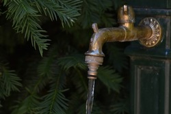 Water flowing from vintage rusty garden tap or outdoor faucet, water shortages and heatwaves in Europe concept, hydration