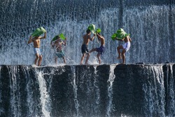 Boys were having fun by playing water in an artificial dam on the Tukad Unda dam, Bali, Indonesia. Bali island is a popular tourist destination in the world. Happiness, joyfull, friendship concept
