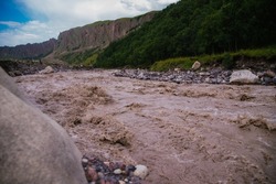 Muddy river water. Spring flood. Dirty muddy water with a whirlpool and white foam close-up.A mountain river or stream raging during a flash flood.