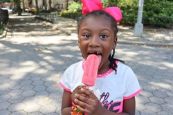 Happy little girl with pink ice cream popsicle outdoors