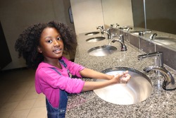 Cute Kid washing hands in public bathroom sink