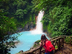 Young woman looks out over a picturesque rain forest waterfall in Costa Rica.