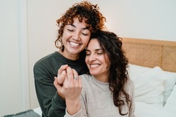 Gay female couple surprising lover with engagement ring in bed at home - Lgbt lesbian love and romance concept