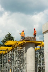 Builders are installing reinforced concrete structures on concrete columns during the construction of a road bridge.
