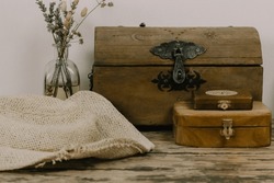 Antique wooden boxes and a vase of dry wildflowers on an old table. Rustic still life with memory about the past. Rusty style chest walnut box for jewelry. Magical faded background. Pirates theme.