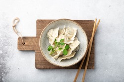 Korean dumplings with soy sauce in a ceramic bowl on a light background , asian food, view from above