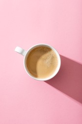 cup of coffee on a pastel pink background, top view, photography with contrast shadow