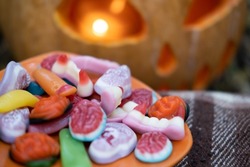 Halloween background. scary candies on a plate near pumpkin with candle