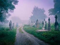 Mystical fog in an old abandoned cemetery. Foggy morning in a spooky cemetery. Stone crosses, ruins and graves.