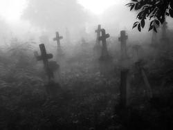 Dark ancient cemetery in the fog. Crosses and graves in a spooky abandoned cemetery. Place of burial. 