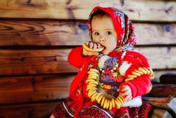 little girl in a Russian costume. Little girl in traditional Russian folk costume. Russian children. Portrait of a girl in the Russian style on a wooden brown background.