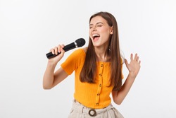 Young pretty woman happy and motivated, singing a song with a microphone, presenting an event or having a party, enjoy the moment