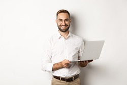 Business. Sucessful businessman working with laptop, using computer and smiling, standing over white background
