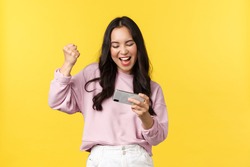 People emotions, lifestyle leisure and beauty concept. Enthusiastic asian girl gamer playing on mobile phone, tilting smartphone to pass level in game, smiling amused, fist pump as winning