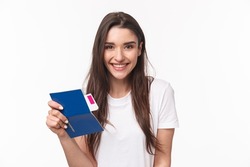 Travelling, holidays, summer concept. Close-up portrait beautiful young woman with long hair, traveller sitting in airport, holding passport and airplane ticket, going for vacation, white background