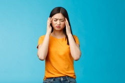 Distressed tired asian woman dark haircut cringe touch temples, suffer huge migraine need painkillers, painful headache, feel dizzy, stand blue background intense drained
