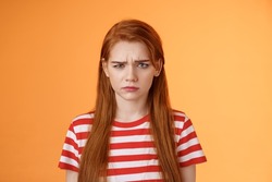 Close-up moody upset childish redhead girl, sulking unfair situation, frowning upset, complaining disappointed, pouting offended, stand uneasy perplexed orange background, whining displeased