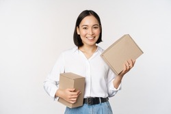 Concept of shopping and delivery. Young happy asian woman posing with boxes and smiling, standing over white background