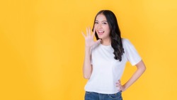 beautiful Asian young woman screams announce the good news or promotion , Excited surprised girl , holding hands near her face with open mouth Herald news promotion isolated on yellow background