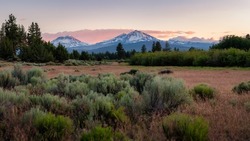 Three Sisters Mountains during sunset in Central Oregon as seen from Sisters, Oregon just outside of Bend in Central Oregon just east of the Cascades and Three Sisters Mountains. 