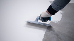 Worker applying a white epoxy resin bucket on floor
