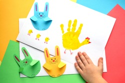 Easter card with a child's palm print with your own hands. Yellow chicken with chickens and paper bunnies