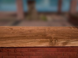 Rustic wooden bench, weathered countertop and a red brick wall, with blurred background. Product backdrop display and empty background.