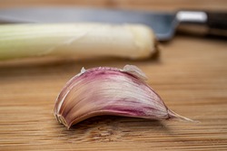 Garlic clove  (Allium sativum) with spring onion and knife on a kitchen board