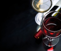 Glass of red and white wine on black background. Wine list design menu with copyspace. Alcohol beverage card backdrop.