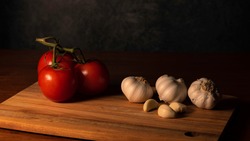High Contrast of Ripe Tomatoes and Garlic on wood cutting board
