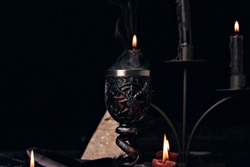 Witchcraft composition with candles, magic book and pentagram symbol. Altar for satanic rituals. Black magic and occult objects.