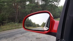 View of the forest and the road to the side mirror of my car