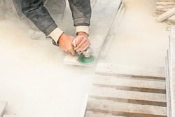 A man polishes a granite slab with a grinder. Work on stone with an angle grinder. A worker polishes a white stone.