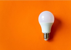 White energy saving light bulb isolated on an orange background with copy space. Concept of eco-friendly life. Minimal thing. LED white bulb, concept of new idea. Minimal think.