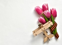 Banner for May 9. Pink tulips, St. George ribbon and wooden plane on a white background. The concept of the Great Victory Day 941-1945 and Defender of the Fatherland Day. Flat lay, copy space 