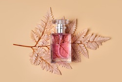 Perfume Bottle with autumn leaf on pastel background. Beauty concept